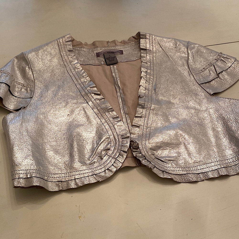 Silver leather shrug with one rhinestone fastener.  Fits medium/ small frame.